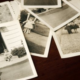 Mehrere schwarz-weiß Fotos liegen über- und untereinander auf einer schwarzen Unterlage
