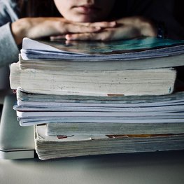 Schülerin hinter einem Stapel Bücher
